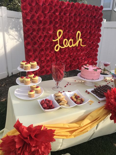 Belle birthday theme party . Yellow and red decorations . Simple dessert table set up . Backdrop are paper red roses with child’s name in the middle . Red Yellow Birthday Theme, Yellow And Red Party Decor, Red And Yellow Decorations Party, Red And Yellow Graduation Party Ideas, Rose Birthday Party Theme, Red Roses Themed Birthday Party, Red Roses Party Theme, Red Rose Party Theme, Red Roses Birthday Party Ideas