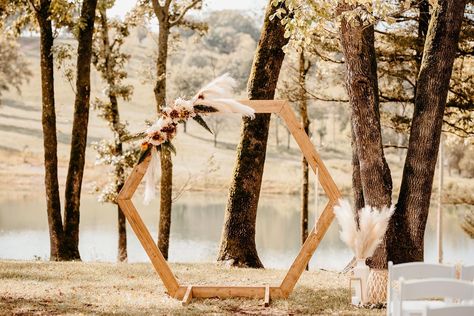 Outdoor wedding ceremony, wooden octagon shaped backdrop/arbor, muted peach color palette, pampas grass, desert color palate, setting in the tress with the sun setting and water behind the arbor. Simple Arch Decoration Wedding, Wedding Hexagon Arch, Arches Decor, Wedding Hexagon, Hexagon Backdrop, Hexagon Wedding Arch, Wedding Canopy Outdoor, Simple Wedding Arch, Hexagon Arch