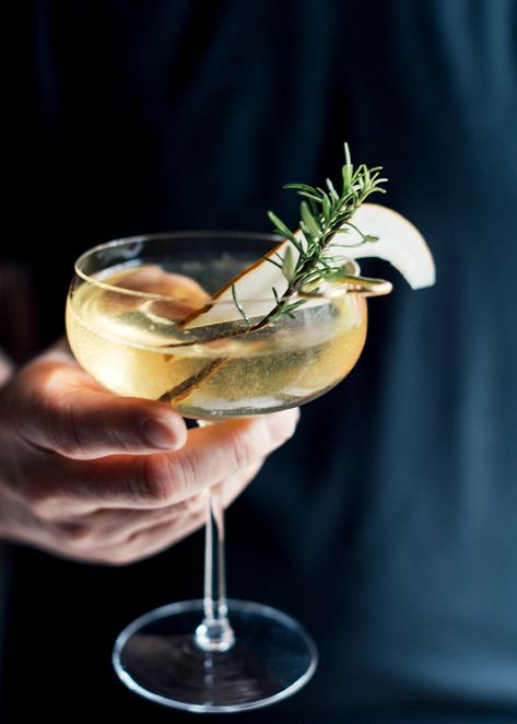 A hand grasping a modern coupe glass filled with a golden liquid is set against a dark black cloth, probably the shirt of the person holding the drink. A slice of pear and sprig of rosemary garnish the drink. Pear Syrup Recipe, Pear Simple Syrup, Pear Syrup, Elderflower Champagne, Elderflower Cocktail, Champagne Recipe, Late Autumn, Winter Cocktails, Rosemary Sprigs