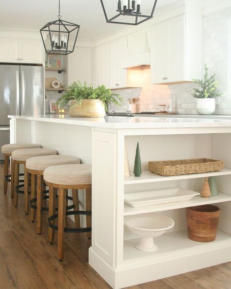 I always need more storage space in my home, so I may have to copy this designer and add some built-in shelves to the end of my kitchen island. The added space is perfect for displaying those items that are seldom needed but nice to keep on hand. I'm also captivated by the use of pine boughs as decorations on the island and kitchen counter, adding an organic touch to the white cabinets and counters. Shelves On Kitchen Island, Island With Shelf On End, Island With Shelves On End, Kitchen Island End Storage, Kitchen Island Shelves Decor, End Of Kitchen Counter Ideas, Kitchen Island Shelves On End, Kitchen Island Side Panel Storage, Side Counter In Kitchen