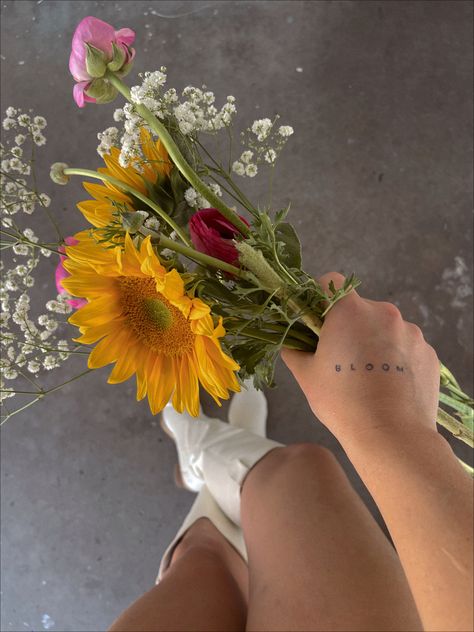 Hand holding bouquet of wildflowers with BLOOM tattooed on back of hand white cowgirl boots Bloom Tattoo Words, Blooming Tattoo, Bloom Tattoo, Hand Tattoo, Word Tattoos, Tiny Tattoos, Simple Tattoos, Hand Tattoos, Small Tattoos