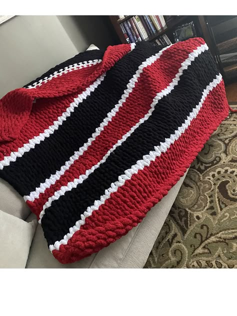 The Georgia Bulldogs chunky knit blanket is a bold and cozy piece perfect for fans of the team. The blanket features thick, oversized yarn that is hand-knit, giving it a luxurious and plush texture. The primary color is a deep, rich red, representing the Georgia Bulldogs' iconic color, with bold black and white stripes or accents woven into the design to further emphasize the team's spirit. 60"X62" The blanket's chunky stitches create a visually appealing and tactile pattern, adding to its warmth and comfort. It's large enough to be a perfect companion for game days, whether at home or in the stadium, offering both style and coziness. This blanket is not only practical but also a statement piece, embodying the fierce pride and loyalty of Georgia Bulldogs fans. Chunky Blanket Pattern, Chunky Knit Blanket Pattern, Chunky Yarn Blanket, Chunky Blankets, Football Blanket, Yarn Blanket, Giant Yarn, Go Dawgs, Chunky Crochet Blanket