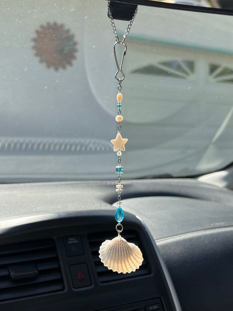 Coastal Car Charm 🌊 This is my FAVORITE charm at the moment <3 looking at it hang in my car makes me feel like i'm driving to the beach <3 I hand drilled the shell & put lots of love into this design <3 Made with Stainless steel findings * Glass beads * Shell beads * Cultured pearl  Ideas on what to use it for: - Rear view mirror charm - Window decor (The charms look so beautiful when the sun hits them!) - Wind chime / Outside decor - Room Decor - Anything you wish to decorate <3  Every charm is designed and made by me. Since it's made-to-order, you'll be receiving a charm that was handcrafted specifically for you 💌   This charm includes small stones, and glass beads that are delicate. It will be packaged in bubble wrap but it is important to handle this (and all other charms) with care Homemade Car Accessories, Car Accessories Hanging, Cute Beachy Car Decor, Ocean Car Accessories, How To Make Car Charms Rear View Mirror, Decorating Car Ideas, Diy Rearview Mirror Charm, What To Make With Shells, Diy Car Charms Rear View Mirror