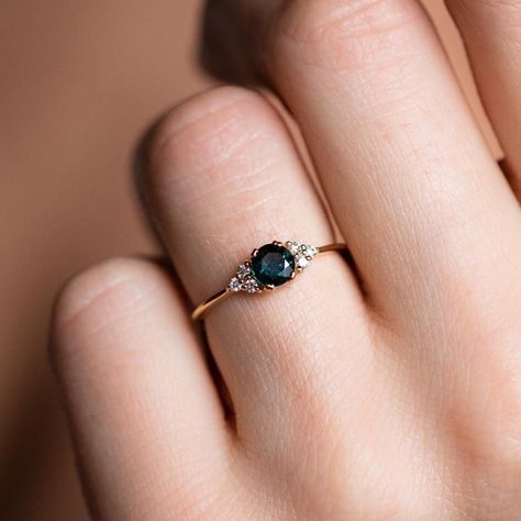 Inspired by the stars, the Lune Ring showcases a captivating teal sapphire, reminiscent of a celestial body, surrounded by a halo of brilliant white diamonds. This unique alternative engagement ring, stunning on either hand, embodies elegance and individuality.  Handmade with care, crafted in 14k solid yellow gold and featuring a 4.5 mm teal sapphire and 0.09 ctw of diamonds.  Allow 4-6 weeks for creation. Ring Board, Rings Sapphire, Parti Sapphire, Green Sapphire Engagement, Alternative Engagement Ring, Blue Green Sapphires, Teal Sapphire, Engagement Inspo, Bespoke Engagement Ring