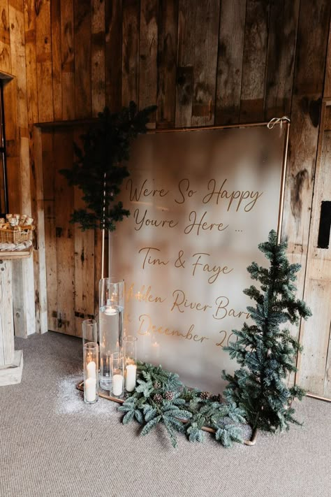 Large frosted glass welcome wedding sign with gold font and candles in glass holders with fur tree and pinecone decor Groom And Groomsmen Outfits, Christmas Gift Exchange Ideas, Pinecone Decorations, Pinecone Decor, Gift Exchange Ideas, Fairy Lights Wedding, Fur Tree, Welcome Wedding Sign, Gold Font