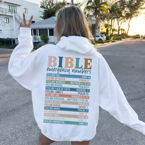 We produce the best quality designs for you like Bible Sayings Hoodie. Enjoy comfort and elegance.  Size: If you like a comfortable fit, you can increase your size selection by one size. If you're slim cut lover, please please make one size smaller. Wash Care Instruction: Please wash the product with cold water and turn inside out. Please do not dry at high temperature. Do not apply high pressure to the printing part while ironing on the product. If possible, iron the printing part on the baking Bible Verse Sweatshirts, Cute Christian Sweatshirts, Verses From Bible, Sweatshirt Sayings, Bible Emergency Numbers, Emergency Numbers, Bible Sayings, Christian Sweatshirts, Christian Clothes