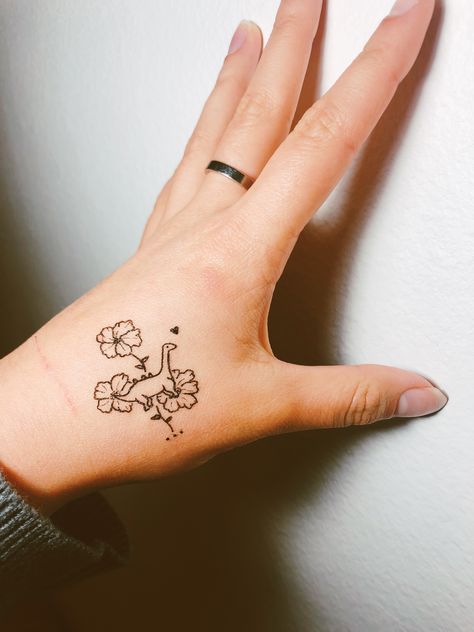 Dainty dinosaur tattoo with hibiscus flowers! Womens Dinosaur Tattoo, Matching Sister Tattoos Dinosaur, Dino Flower Tattoo, Dinosaur Tattoo For Daughter, Matching Dinosaur Tattoo Best Friends, Dino With Cowboy Hat Tattoo, Pretty Dinosaur Tattoo, Matching Tattoos Dinosaurs, Dinosaur And Flower Tattoo