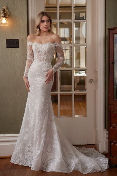 Step into a bygone era of timeless elegance with our vintage-inspired fitted wedding dress, Talisa. Her delicate off-the-shoulder long sleeves evoke a sense of old-world romance, while her exquisite floral lace overlay adds a touch of ethereal beauty to every movement. Designed with a modest straight neckline, this gown exudes grace and sophistication. And with meticulous button details adorning her high back and the cuffs of her long sleeves, the allure of this dress is simply irresistible. Modest Neckline Wedding Dress, Calla Blanche Wedding Dress, Statement Wedding Dress, Calla Blanche, Sheath Wedding Dress Lace, Cape Wedding Dress, Vintage Wedding Dress, Bridal Elegance, Long Sleeve Wedding Dress Lace