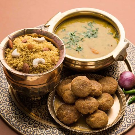 An authentic dish from Rajasthan, dal baati churma is quite popular in the region. The interesting origins of this classic dish arise from the time of wars. The dish has three parts and so does its history. The baati was brought in by Bappa Rawal to feed the soldiers of the Mewar kingdom. The dough of wheat was left to bake in the sun while the soldiers were away at war. On their return, they could eat it with fresh curd. Similarly, the churma followed when one of the cooks of the Guilhot dynast Churma Recipe, Spiced Lentils, Rajasthani Food, Best Fast Food, Best Street Food, Indian Street Food, Classic Dishes, Best Dishes, Best Places To Eat