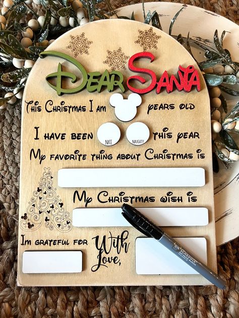 This reusable mickey Santa letter sign is perfect for taking yearly Christmas photos. They are easy to write on with any dry erase marker (marker not included). Details: Each sign measure 8.7 inches wide by 12.3 inches tall, and is cut from natural maple wood. The lettering is printed on with permanent ink and the dry-erase pieces are 3D/raised from the back board. Because these are cut from real wood, there will be natural variations in colour and wood grain. Santa Board, Cnc Machine Projects, Dear Santa Letter, Grinch Ornaments, Laser Cut Wood Crafts, Photo Sign, Letter To Santa, 3d Laser, Christmas Sign