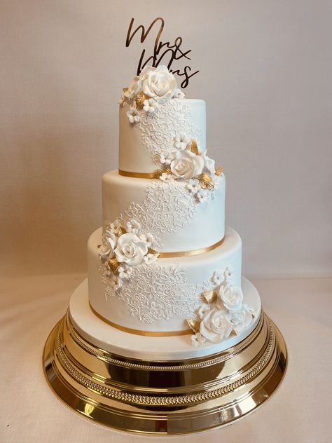 Amberley, popular 3 tier design decorated with edible lace detail and clusters of sugar flowers in white and gold, perfect for a festive Chrismas season wedding Wedding Cake Designs Gold And White, 3 Tier Wedding Cakes Simple Elegant, Cream And Gold Wedding Cake, 3 Tiers Wedding Cake, Modern Two Tier Wedding Cake, 3 Tier Wedding Cake White And Gold, Ivory And Gold Wedding Cake, Wedding Cakes White And Gold, White And Gold Cake Wedding