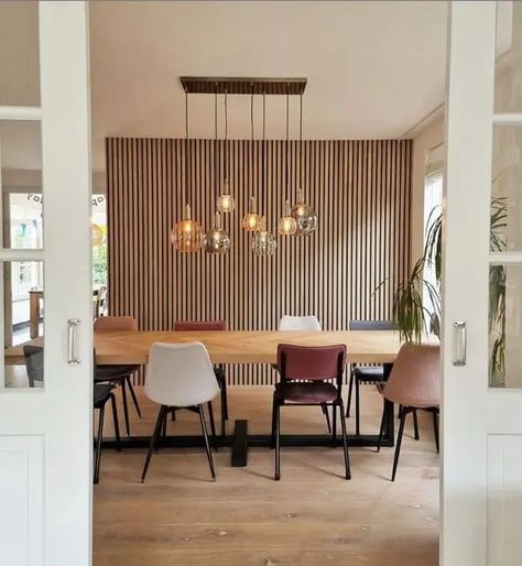 a stylish dining room with a wood slat wall, a stained table, mismatching chairs, a cluster of pendant lamps and potted plants Wall Panel Diy, Dining Room Paneling, Monochromatic Living Room, Slat Wall Panel, Mid Century Modern Dining Room, Dining Room Accents, Wall Paneling Diy, Stylish Dining Room, Contemporary Seating