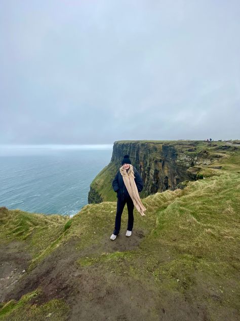 Woman at cliffs of Moher photo idea. Long neutral scarf and black beanie The Cliffs Of Moher, Cliffs Of Moher Aesthetic, Ireland Hiking Outfit, Cliffs Of Moher Outfit, Ireland Instagram Pictures, Ireland Travel Aesthetic, Ireland Photo Ideas, Ireland Photoshoot, Ireland Aesthetic Outfits