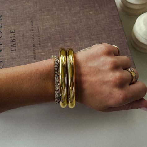 Noor Bangles back in stock 🤍🎀 These 18k gold irregular bracelets are stunning with a high-gloss shine and a natural flowing shape. We highly recommend stacking and layering these bangles to give a much more elevated look! You can also layer them with the tennis bracelet as seen in the second frame 🙂‍↔️ Price: N12,000 only. Please note that bangles are sold individually and not in stacks Chunky Bangle Bracelets, Gold Thick Bracelet, Gold Bracelet Bangle, Chunky Gold Jewelry, Gold Bracelets Stacked, Open Bangle Bracelet, Gold Bangles For Women, Stackable Bangles, Luxe Jewelry