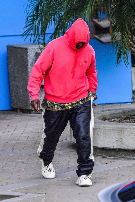 Kanye West steps out in Los Angeles in a bold red hoodie with leather pants, a camo top and Yeezy Foam Runners, June 30. #kanyewest #streetstyle #yeezy #adidasyeezy Yeezy Foam Runner Outfit, Foam Runner Outfit, Runner Outfit, Yeezy Foam Runners, Kanye West Outfits, Kanye Fashion, Men Streetwear Fashion, Runners Outfit, Kanye West Style