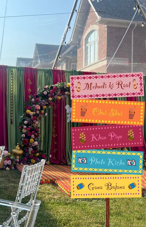 Want to make your Mehndi or Dholki event special? These FIVE signs are the perfect touch to your event. They are versatile and can be used for several of your wedding events, indoor or outdoor.  They are super easy to use.  Dimensions are: 24.5" x 8" for each sign! Once you purchase them, you will be sent a PDF containing all 5 of these signs. All you need to do is print them out and done!  Arrange them however you like, I recommend arranging them on a picket sign or a post as you can see in the pictures.  Please get in touch with me if you have any sort of questions! Enjoy. Mehedi Programme Decorations, Mendhi Entrance Ideas, Mehendi Gate Decor, Mehndi Celebration Ideas, Wedding Mehndi Decoration, Mehndi Sangeet Decoration, Pakistani Sangeet Decor, Decoration For Mehendi Ceremony, Mendhi Decoration Ideas Outdoor