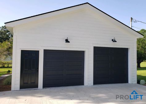 White Siding Black Garage Door, Tall Garage Doors, Barndominium Black Garage Doors, Black Plank Garage Door, Anove Garage Doors, Brown Garage Door, Farmhouse Outside, Pole Barn Garage Doors Long Panel, Black Garage Doors