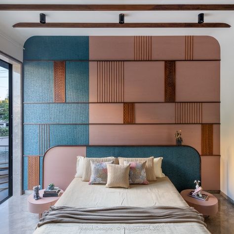 Step into a bedroom in Shobha where bold design meets thoughtful craftsmanship. The bed back wall is an artistic composition, vertically divided off-center into two contrasting sections. One side features a dyed veneer in a soft pink tone, while the other boasts an MCM textured panel painted in a striking blue. The interplay of these colors creates a dynamic yet balanced backdrop, further enhanced by the addition of horizontal wooden lines, vertical rafters, and a carved wooden panel. The wal... Modern Artistic Bedroom, Bedroom Reference, Bed Back Wall, Artistic Composition, Anime Bedroom, Worli Painting, Artist Bedroom, Bedroom Interior Design Luxury, Indian Interiors