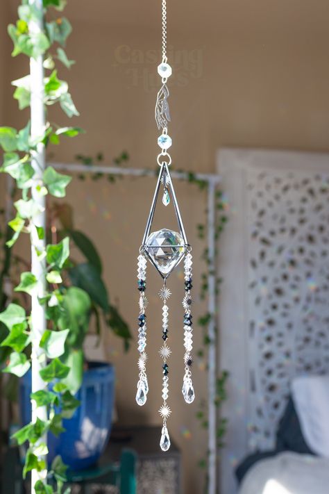 Elevate your space with our stunning Black Whimsical Suncatcher! Handcrafted with high-quality crystals, this enchanting piece captures sunlight, creating mesmerizing patterns and ethereal light displays that add a touch of magic to any room. ✨ What is a Suncatcher? A suncatcher is a decorative item designed to hang in windows, refracting light to fill your space with vibrant colors and unique designs. This gothic crystal suncatcher not only enhances your decor but also promotes positive energy, Gothic Suncatcher, Refracting Light, Crystal Suncatchers Diy, Prism Suncatcher, Unique Window, Diy Suncatchers, Ethereal Light, Window Suncatchers, Hanging Crystal