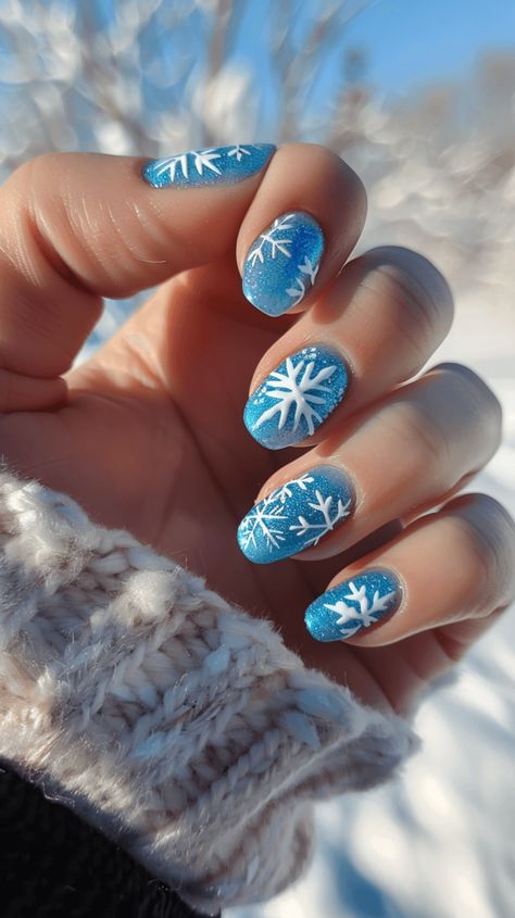 A manicured hand with icy blue nails with white snowflake designs representing Elsa from Frozen. Icy Snowflake Nails, Nail Ideas Snowflake, Snowflake Nail Art Designs, Frozen Theme Nails, Elsa Nails Frozen, Blue Christmas Nail Art, Frozen Nails Disney, Xmas Nails Snowflake, Blue Winter Nails Short