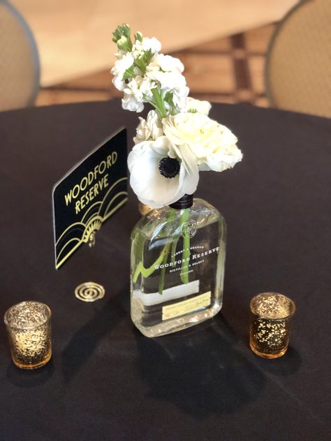 We used multiple bourbon bottles as vessels, for this great Gatsby inspired wedding. Speakeasy Wedding Centerpiece, Whiskey Bottle Flower Vase, Bourbon Event Decor, Bourbon Wedding Centerpieces, Bourbon Bottles Wedding, Bubbles And Bourbon Party, Whiskey Themed Centerpieces, Bourbon Wedding Decor, Whisky Bottle Centerpiece Wedding