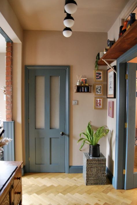 The doorway to a kitchen with a blue-trim accent next to a small gallery wall of framed art. Colour Door Frame, Colorful Moldings And Trim, Blue Trim Kitchen, Eclectic Accent Wall Ideas, Blue Painted Interior Doors, Low Ceiling Color Ideas, Teal Trim Interior, Creative Wainscoting Ideas, Color Trim And Doors