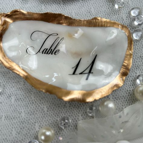 Flat Oyster Table Place Cards, Gold & Natural Place Cards https://www.etsy.com/listing/1748141079 These flat (not cupped) personalized oyster shells are the perfect way to🥂 𝓦𝓸𝔀 your guests at your coastal wedding or event. Your guest will be surprised to know that they have a very special keepsake to take with them. Your tables will be stunning and elegant with the table numbers on these shells that match the guest’s keepsakes. A thoughtful gift that they will always cherish on their very spe... Shell Table Numbers, Oyster Place Cards Weddings, Oyster Table, Coastal Wedding Decor, Sea Glass Wedding, Natural Place, Table Place Cards, Coastal Wedding, Oyster Shells