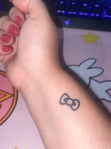 Hello Kitty’s bow tattooed in black ink on wrist Cute Hand Tattoos Small Simple, Hello Kitty Bow Tattoo, Stick And Poke Tattoo Ideas Simple, Simple Stick And Poke Tattoo, Tattoo Hello Kitty, Tatuaje Hello Kitty, Bow Finger Tattoos, Tattoos On Wrist, Bow Tattoos