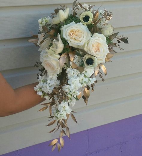 Cascade of white stock, cream roses, panda anenomes accented with gold foliage Gold And Silver Bouquet, Green White Gold Bouquet, Bridal Bouquet With Gold Accents, Gold And White Wedding Bouquet, White And Gold Flower Arrangements, White And Gold Wedding Bouquet, White And Gold Bouquet, Elizabethcore Aesthetic, Restaurant Flowers