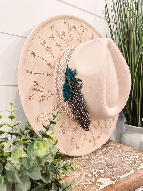 Wildflower Floral Burned Hat, Floral Engraved Cowboy Hat, Sunflower Hat, Sunflower Burned Fedora, Engraved Fedora, Engraved Felt Hat, Boho Hat Elevate your style with our beautifully engraved floral hats! If you want certain colors for the feather/flower detail, please leave a note at checkout. Bands and florals/feathers may shift or fall off during shipping. The hat has an adjustable band on the inside to fit many sizes. One size fits most adult heads. Decorated Felt Cowboy Hats, Custom Burned Felt Hats, Custom Cowboy Hat Ideas, Burned Hat Design, Boho Hats For Women, Hat Burning Ideas, Hat Burning Designs, Western Hats For Women, Cowboy Hat Crafts