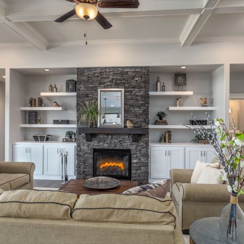 Modern model home with rock fireplace, ceiling fan, floating shelves and lovely living room decor. #fireplace #fireplacedesign #modelhome #modelhomedeocrideas #floatingshelf #livingroomdecor #livingroomdesign #furnitureideas #livingroomdecorideas #floatingshelves #floatingshelveideas #openconceptdesign #ceilingfans #ceilingdesign Fireplaces With Floating Shelves On Each Side, Floating Shelves Over Cabinet Living Room, Living Room Rock Fireplace, Floating Shelf Next To Fireplace, Floating Shelves Fireplace Surround, Fireplace With Shelves On Each Side, Floating Shelves Beside Fireplace, Fireplace With Floating Shelves On Sides, Floating Shelves By Fireplace