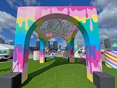 Rainbow coloured pavilion arches over the unicorn garden activation space, with reflective silver streamers hanging from the sky. Scenic painting of dripping rainbow colours adorn its columns. Created for the Unicorn Garden kids event at Docklands in Melbourne. Creative Ideas For Events, Arch Event Design, Corporate Event Entrance Arch Design, Burning Man Art Installation, Event Arch Design, Entrance Arch Design, Event Arch, Docklands Melbourne, Event Activations