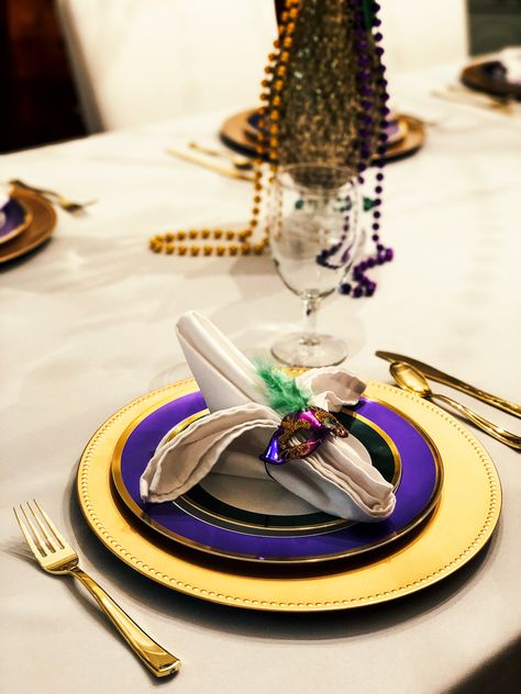 Mardi Gras place setting with miniature mask napkin ring, purple and green rimmed plates on gold charger Mardi Gras Table Setting, Mardi Gras Dinner Party Table Settings, Madi Gras Party, Mardi Gras Tablescape, Mardi Gras Wedding Theme, Mardi Gras Dinner Party, Mardi Gras Dinner, Corporate Gala, Mardi Gras Ball