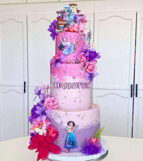 Tall 3 tier cake in shades of pink and purple with Mirabel and Isabela from Encanto covered in fake flowers and sprinkles with the casita on top Buttercream Encanto Cake, Encanto Cake Simple, Isabela Encanto Cake, Isabella Encanto Cake, Encanto Treats, Cake Pink And Purple, 3 Tier Birthday Cake, Tier Birthday Cake, Encanto Cake