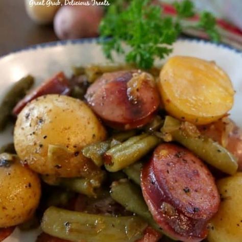 Preheat oven to 400° and spray a 9x13 baking dish with a non stick spray. Wash creamer potatoes, cut in half and add to a sealable gallon size baggie. Add oil, seasonings, pepper and red pepper flakes to baggie. Shake to coat. In a large frying pan, add sausage and water and cook over medium high heat until sausages have browned and most of water has evaporated. Remove sausage from pan and when cool enough add to baggie. Melt butter in frying pan and add onions and garlic, cook until onions ... Sausage And Green Beans, Foil Meals, Bbq Foods, Potatoes Green Beans, Oven Meals, Green Beans Side Dish, Potatoes And Green Beans, Smoked Sausage Recipes, Fish Fingers