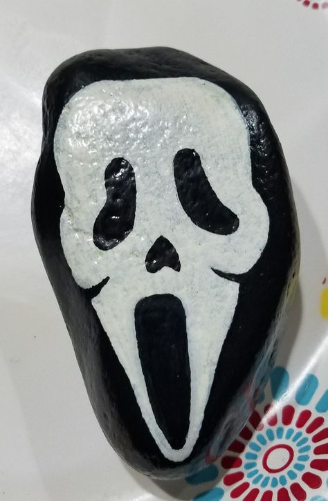 Scream painted rock Scream Rock Painting, Creepy Rock Painting, Dracula Rock Painting, Horror Movie Rock Painting, Painting Rocks Halloween, Goth Rock Painting, Horror Movie Painted Rocks, Beetlejuice Rock Painting, Spooky Painted Rocks