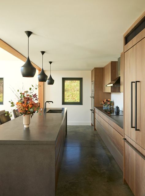 Modern high performance kitchen in sustainable Catskill New York home with wood cabinets and cement countertops Natural Wood Kitchen Cabinets With Concrete Floors, Wood Cabinets Concrete Floor, Cement Floors In House Kitchen, Wood Cabinets With Concrete Floors, Cement Wood Interior, Wood And Cement Kitchen, Cement And Wood Interior, Polished Concrete Floor Kitchen Rustic, Concrete Quartz Countertops Kitchen