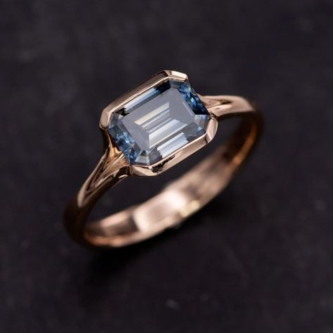 Elevate your engagement game with our stunning Emerald Cut Blue Moissanite Fold 14k Rose Gold Solitaire Ring! This ready-to-ship beauty boasts a sophisticated emerald cut grayish-blue moissanite, elegantly set in a low-profile semi-bezel. Its tasteful blend of luxury and exclusivity makes it the perfect choice to create that unforgettable moment. Tap the link in our bio to order yours now! https://nodeform.com/products/emerald-cut-blue-moissanite-fold-14k-rose-gold-solitaire-engagement-ring-s... Blue Moissanite Ring, Emerald Cut Blue Topaz Ring With Bezel Setting, Blue Emerald Cut Ring With Rose Cut Diamonds, Blue Solitaire Emerald-cut Ring, Timeless Emerald-cut Sapphire Ring With Bezel Setting, Luxury Emerald-cut Sapphire Ring With Tension Setting, Engagement Games, Rose Gold Solitaire Ring, Blue Moissanite