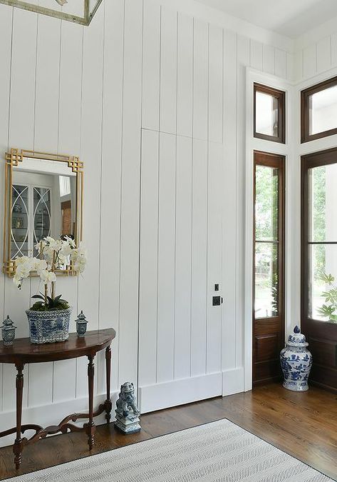 Cottage entry features a jib door with vertical shiplap trim and a gold leaf Greek key mirror over a demilune console table. Hidden Shiplap Door, Shiplap Hallway, Jib Doors, Jib Door, Dark Stained Wood Floors, Shiplap Trim, In Home Library, Bath Goals, Den Library