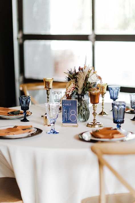 Wedding Reception Tablescape with Unique Blue Debutante Goblet Glassware and Dried Boho Centerpieces |Fall Wedding Design Inspiration Navy Blue And Copper Wedding Table Decor, Navy Terracotta Wedding Table, Navy Fall Wedding Decor, Terracotta And Blue Wedding Palette, Navy Blue Fall Wedding Centerpieces, Terracotta And Navy Centerpieces, Blue And Orange Wedding Table Settings, Navy Rust And Champagne Wedding, Dusty Blue And Amber Wedding