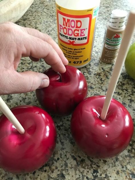 I love Fall decor, and this one is just so fun and looks good enough to eat! Take a look at how I made these, and perhaps you can make a few yourself. First, just pick up some fake apples from the craft store. Remove all the stems from your faux apples, and push the wood dowels into the tops. This how they will look... Now pour some corn cob on a paper plate- you can find this at a pet store! Next, lay a piece of wax paper onto your counter. Then pour some caramel co… Diy Faux Candy Apples, Fake Food Christmas Ornaments, How To Make Fake Candy Decorations Diy, Fake Bake Halloween, Caramel Apples Diy, Fake Candy Decorations Diy, Carnival Christmas, Fake Candy, Fake Food Props