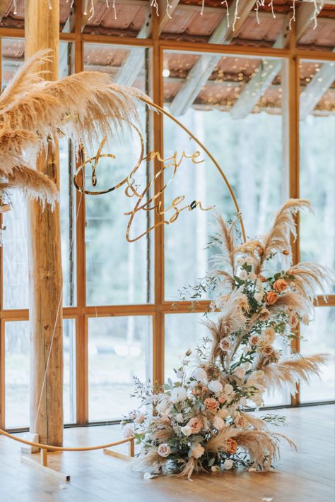 Gold circle arch decorated with pampas leaves and roses, with a gold acrylic die-cut of the wedding couple's name. Circle Arch, Name Decor, Round Backdrop, Dried Pampas, Arch Decoration, Floral Swag, Gold Circle, Floral Arch, Wedding Arch