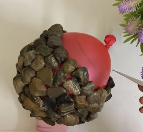 Woman glues stones together around balloon to make cutest stone flower pots Pebble Bowl Diy, Rock Bowls Projects, Rock Flower Beds With Potted Plants Garden Ideas, Rock Bowl Diy, Crafts With Rocks, Diy Decorative Balls, Balloon Diy Crafts, Rock Ornaments, Beach Rocks Crafts