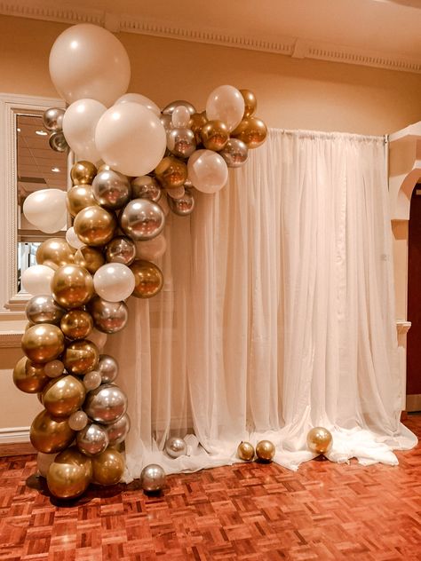 A simple, yet elegant design for a backdrop made from gold/silver/white balloon arch and a white drape backdrop. #eventdecor #balloons #balloonarch #balloondecor #backdrop #drapes #eventrentals Balloon Garland Rectangle Backdrop, Wedding Decoration White And Gold, Backdrop With Balloons On Side, White And Gold Balloon Backdrop, Simple Balloon Arch Backdrop, Elegant Balloon Arch, White And Gold Balloons Decoration, Birthday Balloon Backdrop Ideas, White Drape Backdrop