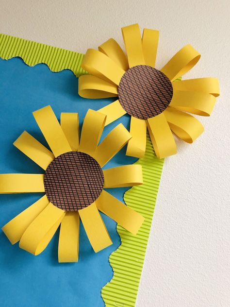 Love these little details!   Supplies needed: construction paper, scissors, ruler, permanent marker, stapler, hot glue.     •Create petals by using construction paper and ruler.  •Cut, bend, and staple together to make flower.   •Use ruler to make lines for the middle of your sunflower  •Glue middle to your flower.   •Attach to board/door or wherever your choose! Flowers For Bulletin Board Diy, Construction Paper Classroom Decor, Fall Crafts Construction Paper, Construction Paper Sunflower, Sunflower Door Decor Classroom, Fall Construction Paper Crafts, Sunflower Bulletin Board Ideas, Chart Paper Decoration Ideas, Sunflower Crafts For Kids