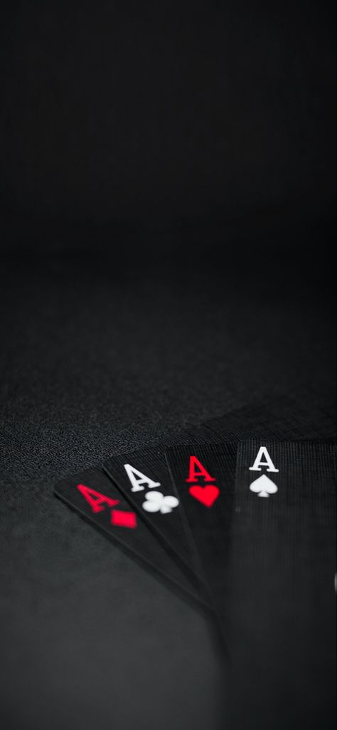 A wallpaper for your device.  Mostly black, very dark, with four cards spread in a fan on a black table or surface.  The order of the cards from left to right: ace of diamonds, ace of clubs, ace of hearts, and ace of spades.  The cards are black with the ace of hearts and ace of diamonds with read font and read symbols, and the ace of clubs and ace of spades with white colored font and symbols. Black Cards Wallpaper, Wallpaper Cards Poker, Red Poker Cards Aesthetic, Ace Of Spades Wallpaper Iphone, Ace Card Wallpaper Iphone, Poker Card Wallpaper, Ace Of Spades Wallpaper, Poker Wallpapers, Black Poker Cards Wallpaper