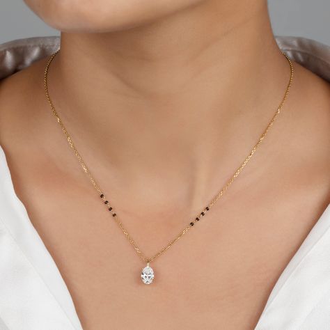 Unveil your unique style with the Nimi Mangalsutra, where classic tradition meets sleek modernity. This standout piece features a stunning vertically-set oval lab-grown diamond, available in various sizes and grades, showcased within a sleek bail pendant for easy customization. Forged from premium 18K solid gold—choose from yellow, white, or rose—this design is accentuated with four distinctive black beads on either side of the chain, each symbolizing strength and direction. The Nimi Mangalsutra New Latest Mangalsutra Design, Elegant Mangalsutra Designs, Gold Chain Mangalsutra Designs, Gold Mangalsutra Designs Latest, Mangal Sutra Designs Gold Modern, Latest Mangalsutra Design 2024, Black Beads Designs Latest, Solitaire Mangalsutra, Gold Mangalsutra Designs Latest Unique