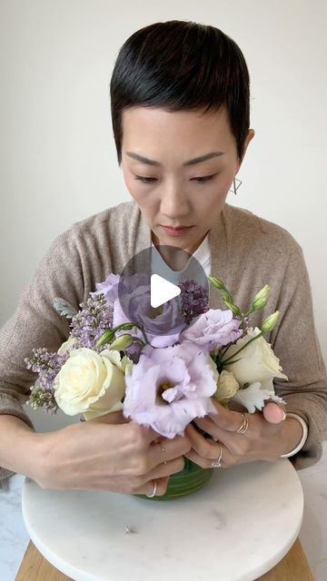 NYC Wedding and Events Florist on Instagram: "I’m a huge lilac fan. Ingredients and steps: ✔️Roses, spray roses, lilac, lisianthus, sweet pea, anemone, and dusty miller.  ✔️ Leaf line the vase.  ✔️ Use my flower food combo: a drop of bleach + a splash of lemon soda.  ✔️ Start with the roses to cross cross the stems in each corner of the vase.  ✔️ Lilacs have woody stems —> help it drink water by splitting the stem for more surface area.  ✔️ Fill in the holes and gaps of the arrangement while balancing out the blooms throughout the vase. ✔️ Save + Like + Share + Follow for more flower arranging   The fluffiness and fragrance of lilacs are irresistible. Who else is a fan? 🙋🏻‍♀️💜  #flowerarranging #floralsesign #floristsofinstagram #flowerclass #flowerdiy #flowerfood #rachelchofloral" Lisianthus Flower Arrangement, How To Arrange Roses In A Vase, Lilac Flower Arrangements, Lisianthus Arrangement, Rose Vase Arrangement, Magnolia Flower Arrangement, Lilac Lisianthus, Lilac Arrangements Simple, Light Purple Floral Arrangements