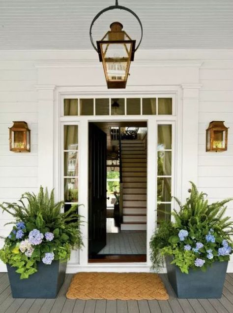 An open front door is flanked by two large square stone planters filled with tropical plants. Purple and blue flowers accent the green leaves. Front Door Planters, Front Porch Plants, Front Porch Planters, Door Planter, Porch Plants, Porch Planters, Building A Porch, Farmhouse Front Porches, Patio Shade