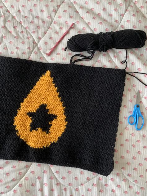 A crochet panel (sample swatch, pattern test) based on a useful pixel grid pattern of Conan Gray's iconic teardrop star symbol from his 3rd studio album "Found Heaven." The pattern contains a black star with a yellow teardrop surrounding it and a black background. Great inspiration and guide for crochet and knit projects surrounding this musical album and its songs/concepts. Crochet Conan Gray, Conan Gray Embroidery, Lovejoy Crochet Pattern, Crochet Teardrop, Conan Gray Teardrop Star, Conan Gray Crochet, Gray Crochet, Conan Gray Sweater, Grey Crochet